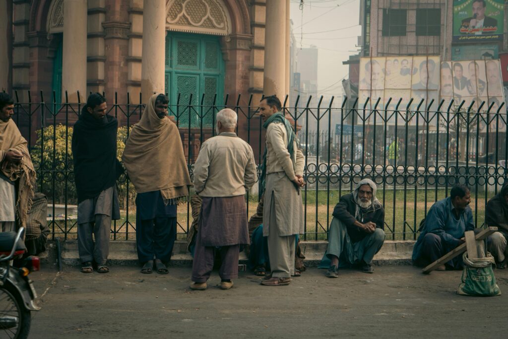 Men gathered for a morning conversation in a foggy Faisalabad street, Punjab, Pakistan.