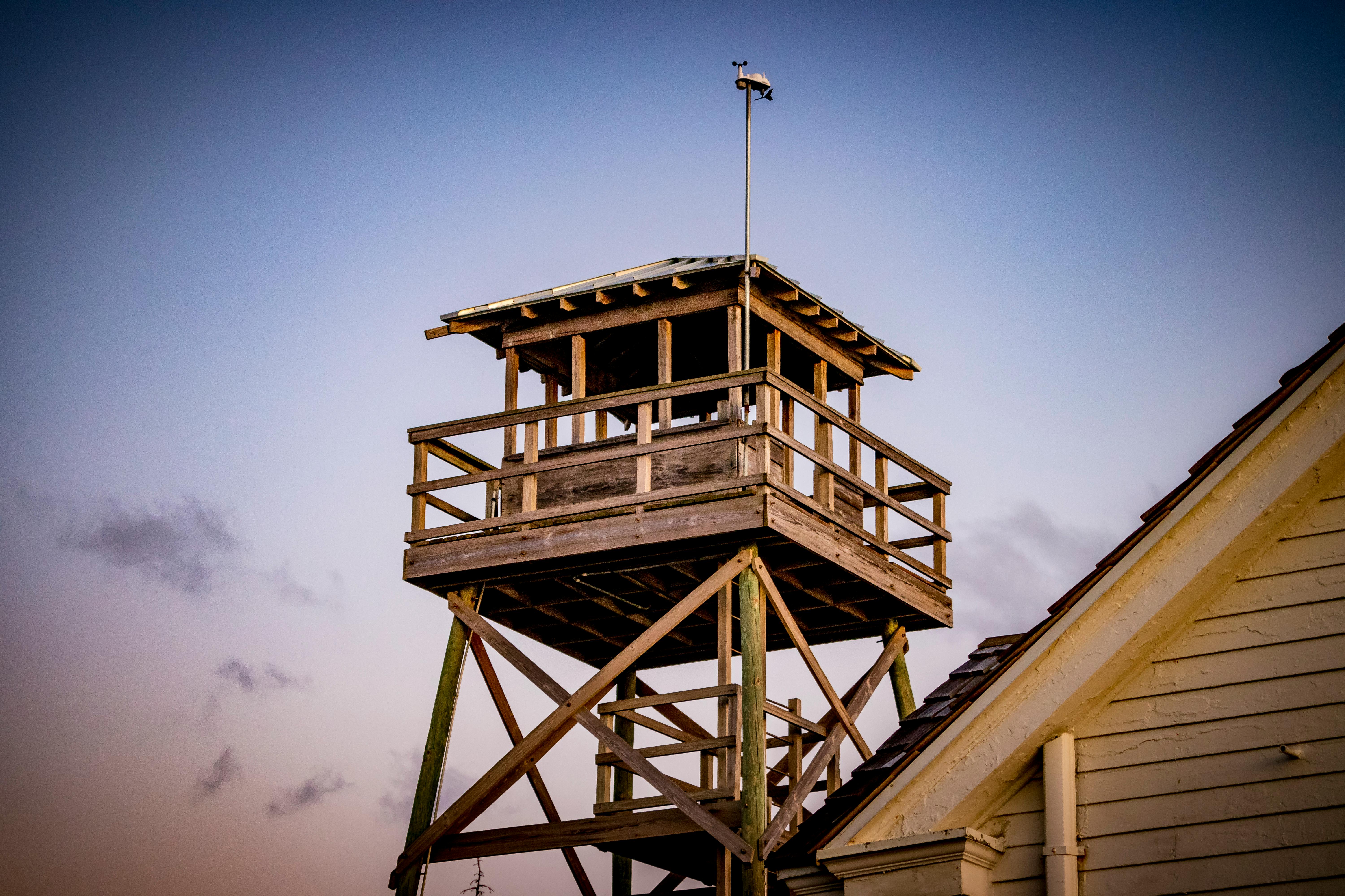 A low-angle shot of a wooden lifeguard watchtower with clear skies, showcasing rustic architecture.