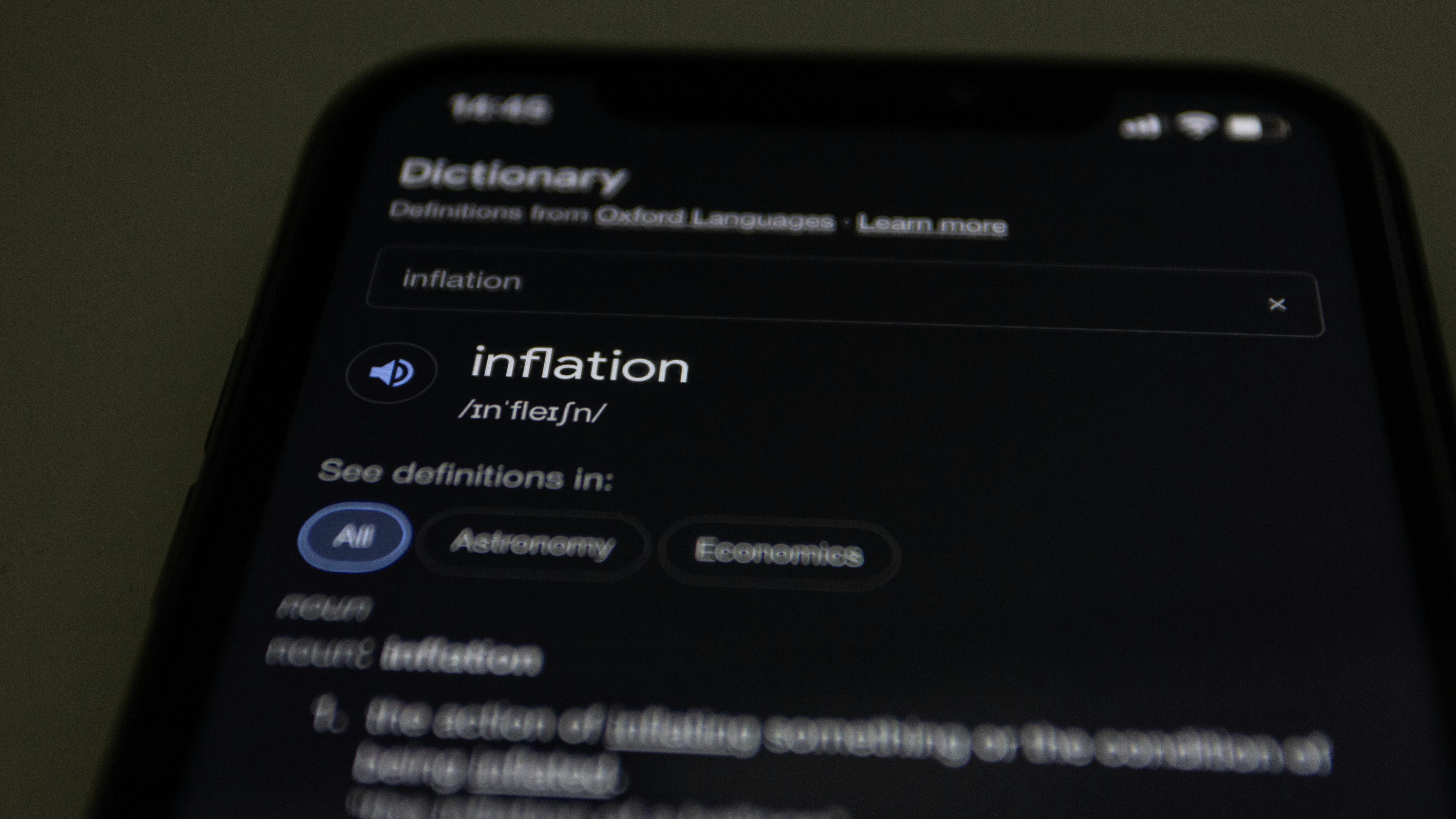 Close-up of a smartphone screen showing the word inflation defined in a dictionary app.
