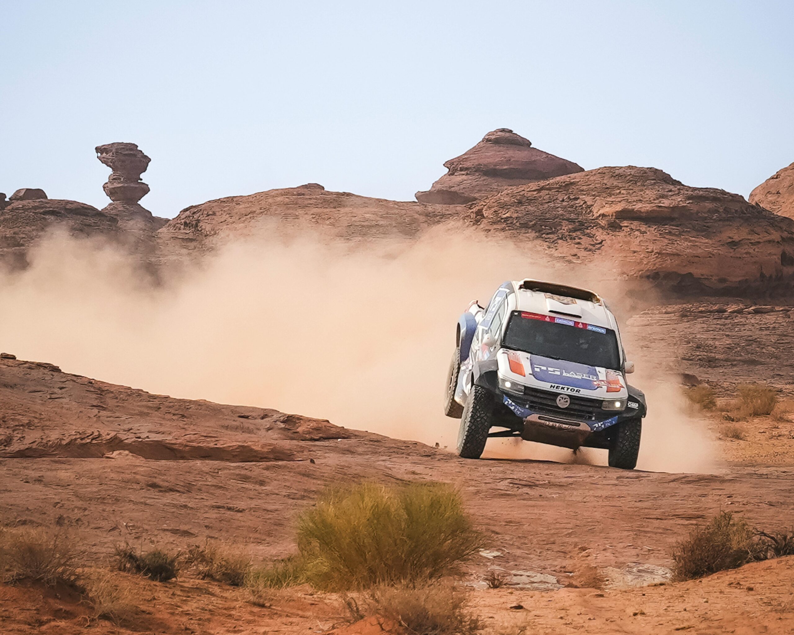 Dramatic off-road vehicle navigating the rocky desert with dust trail.