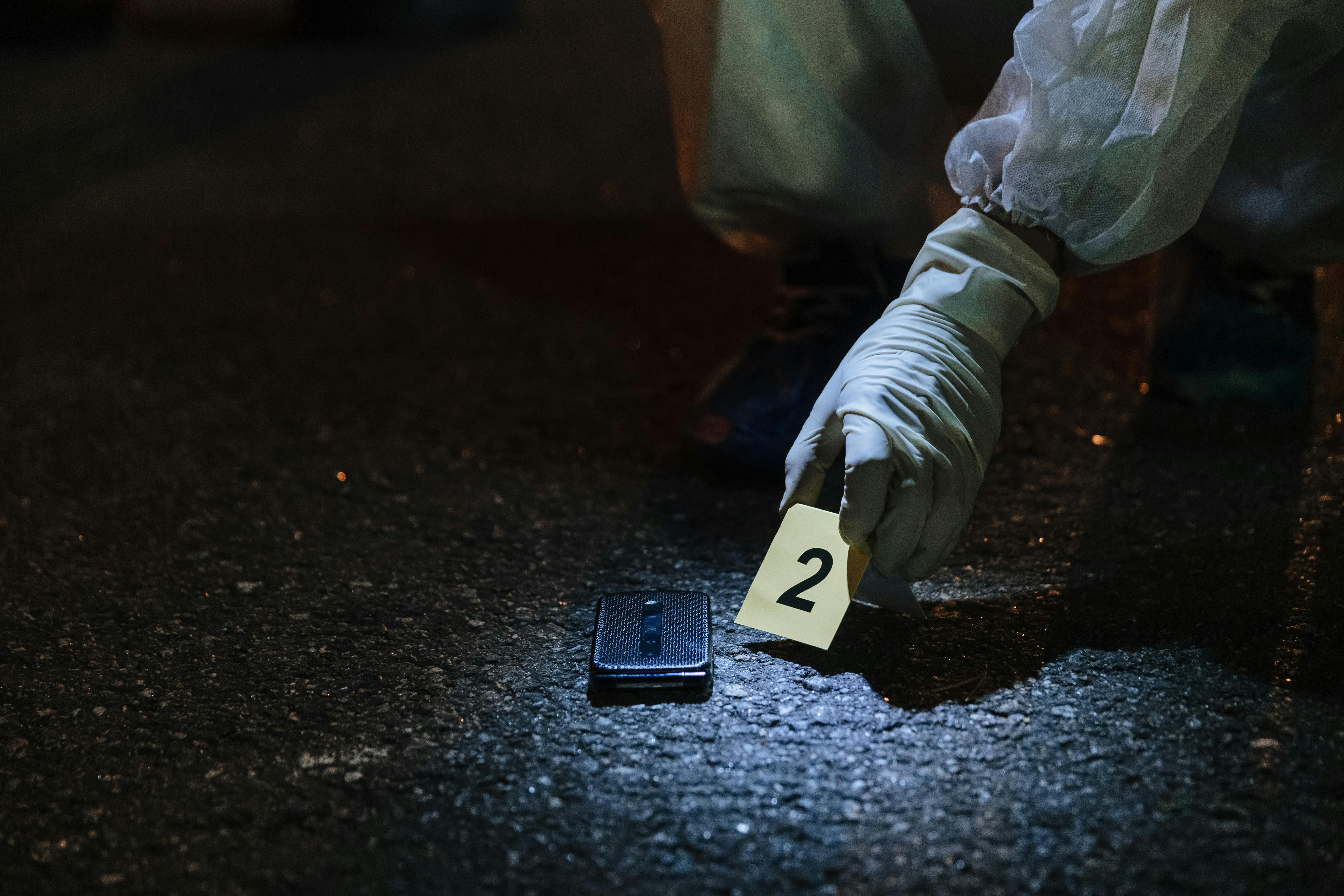 Forensic investigator examining evidence in a city street at night.