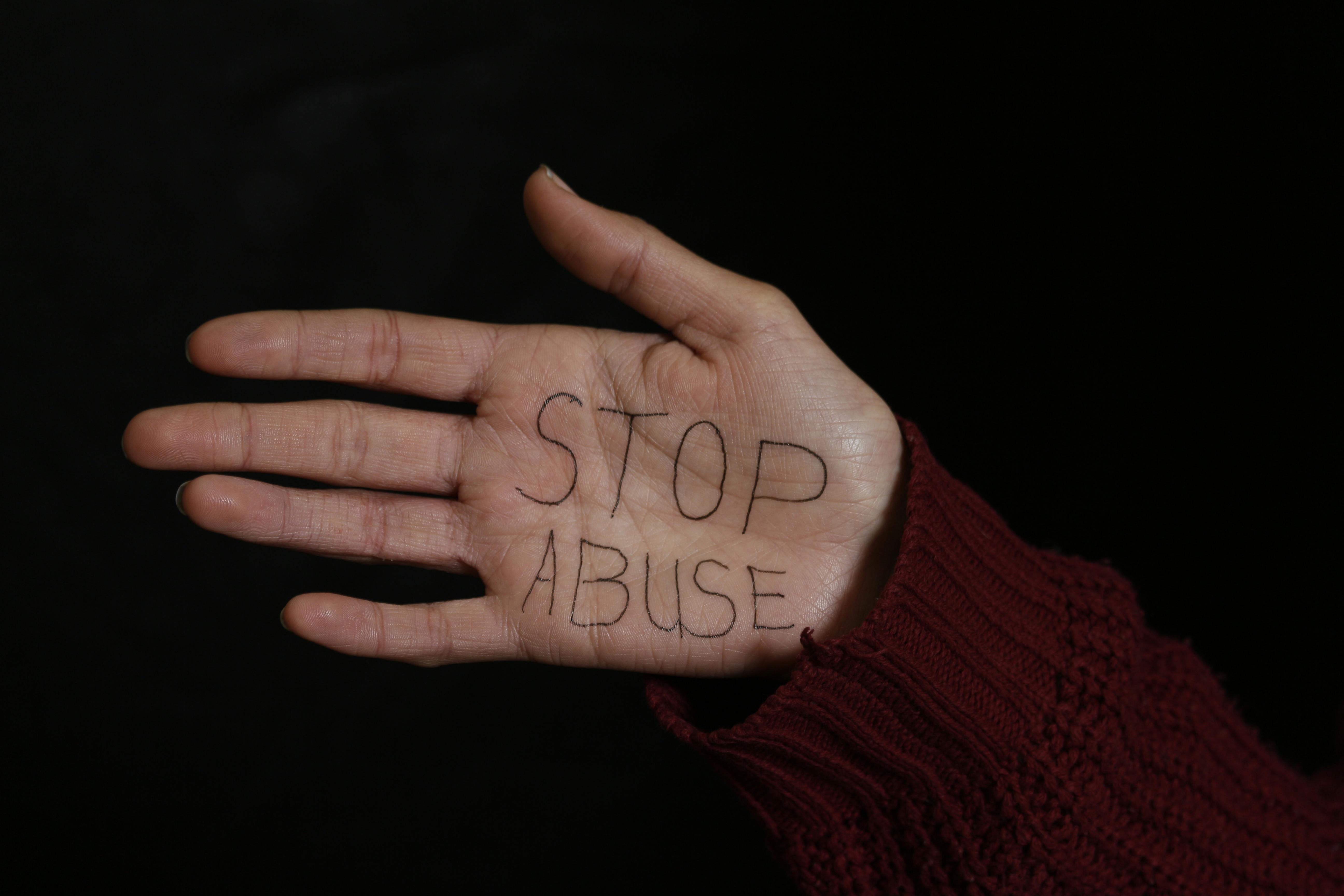A hand with 'Stop Abuse' written on it, symbolizing activism against abuse.