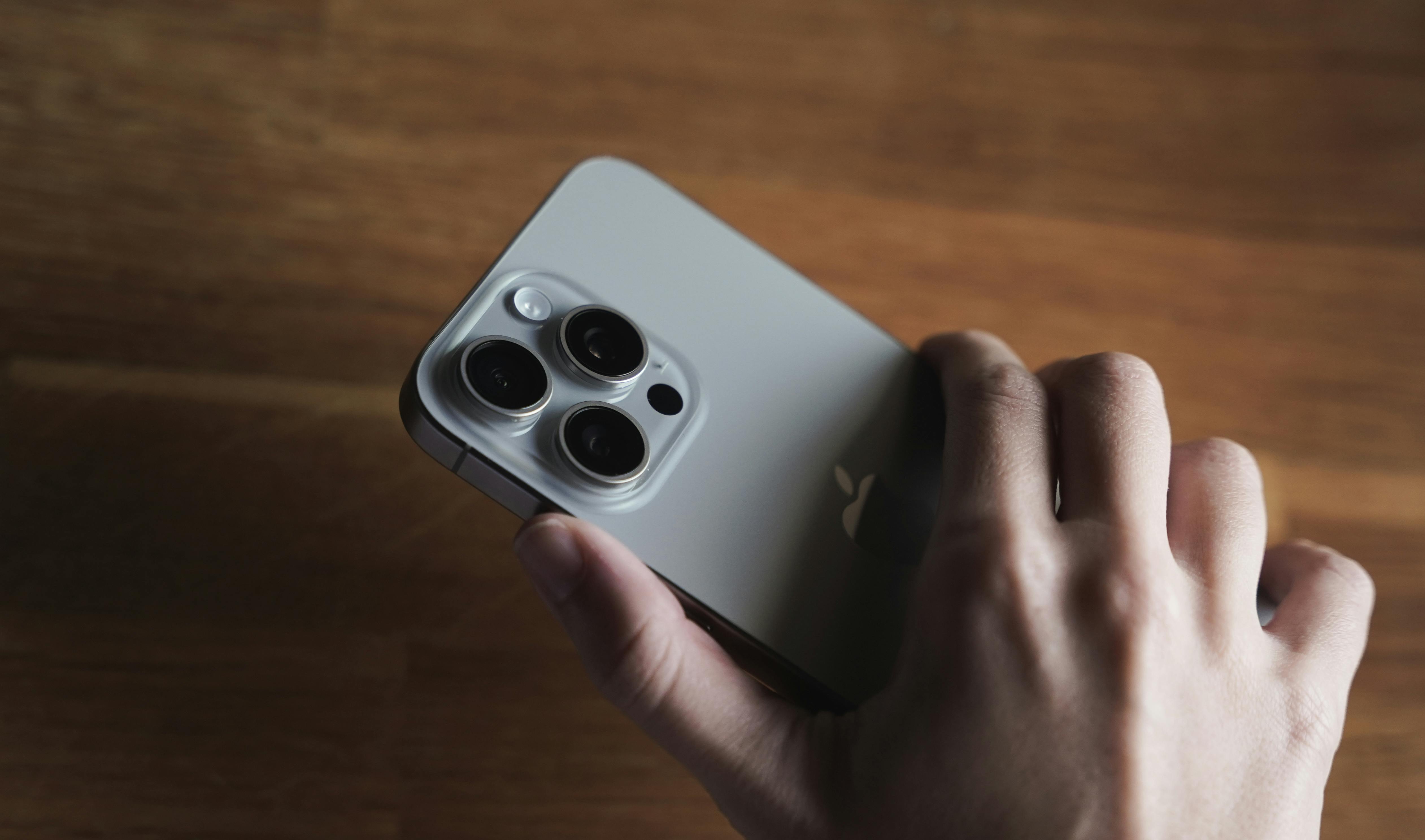 Detailed close-up of a smartphone camera lens held in a human hand, showcasing technology design.