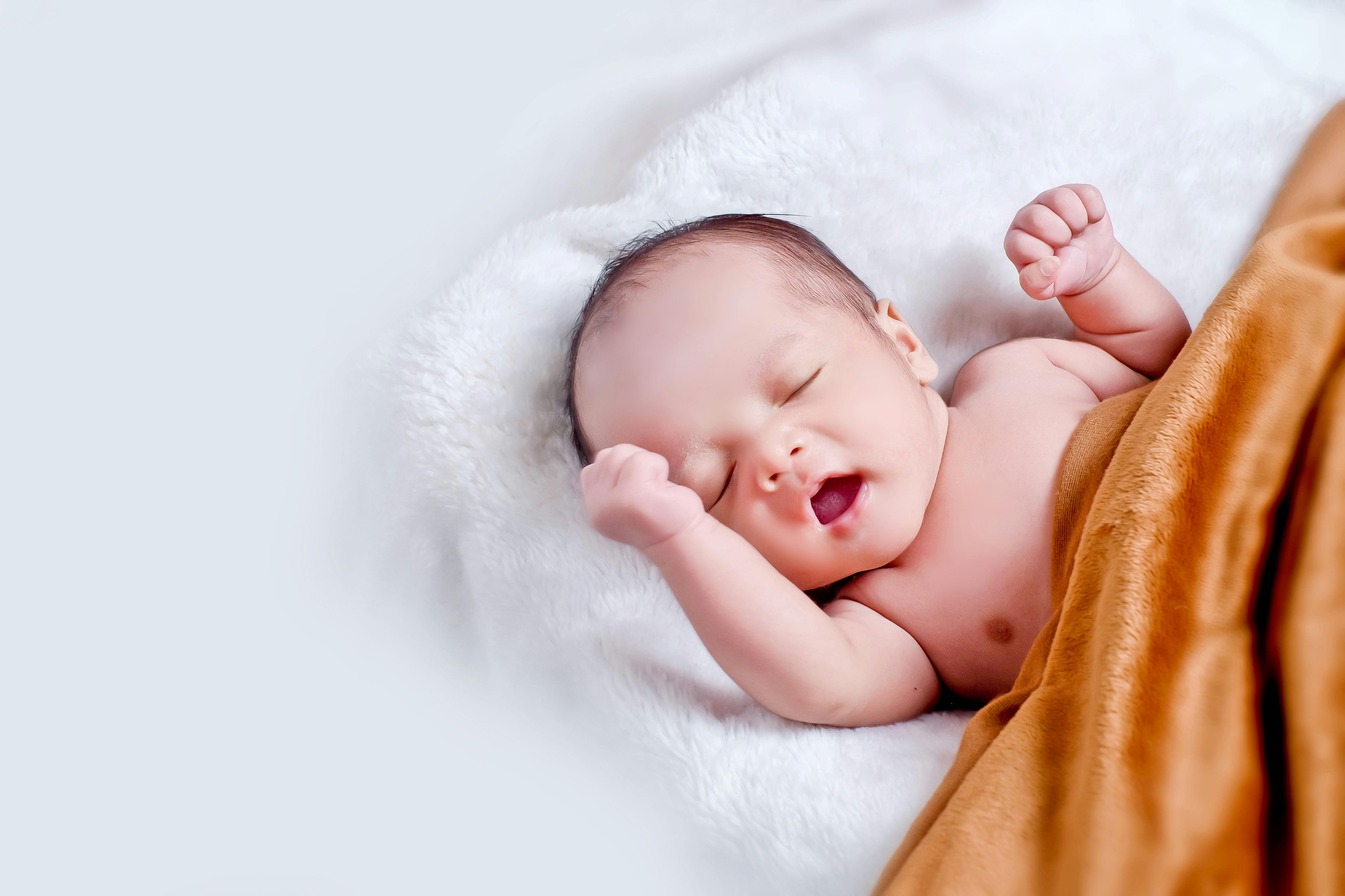 A peaceful sleeping infant wrapped in a soft, warm blanket on a cozy white surface.