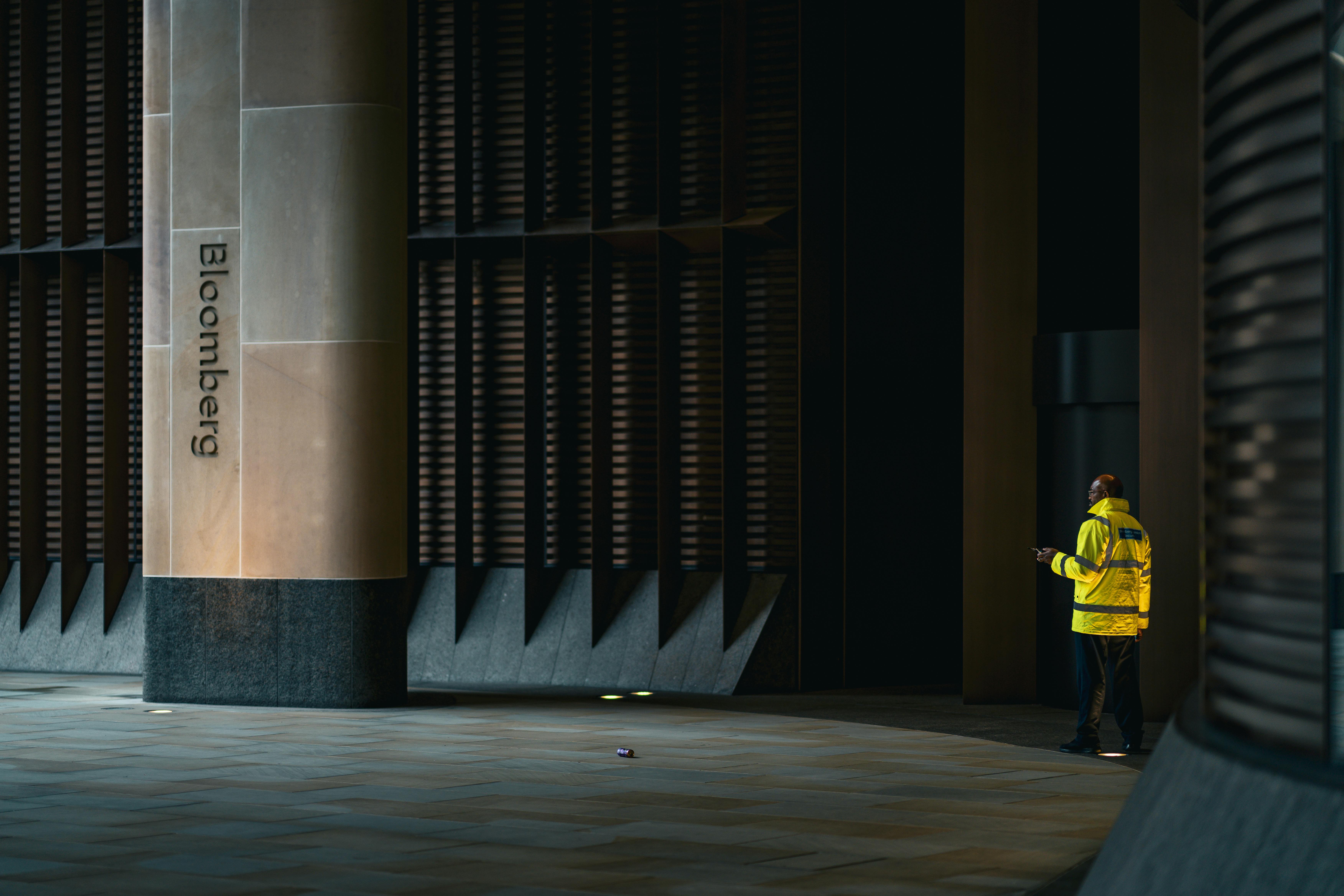 A security guard stands near the entrance of the Bloomberg building in London at night.