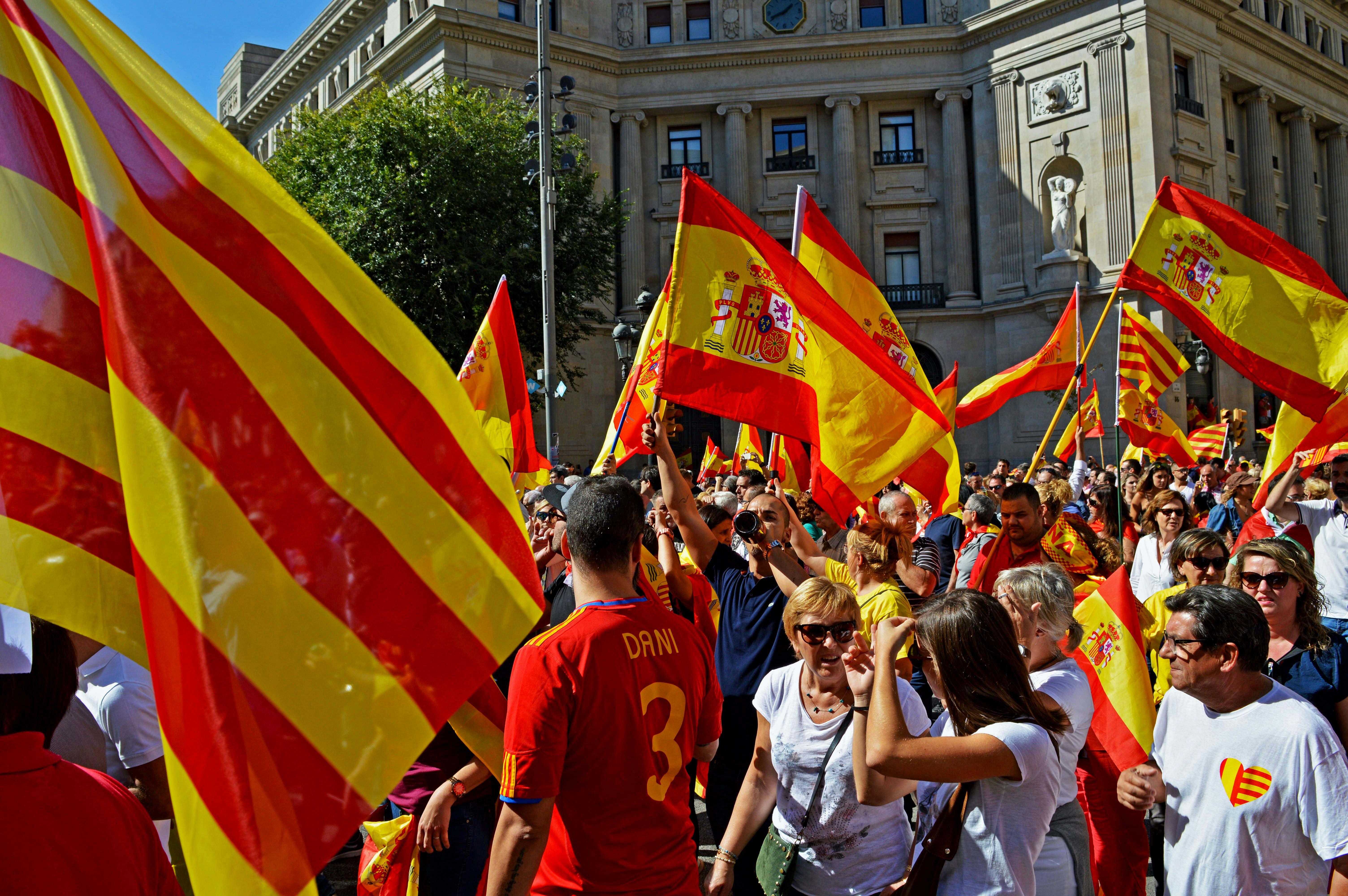 Colorful rally in Barcelona featuring Catalan and Spanish flags and a lively crowd.