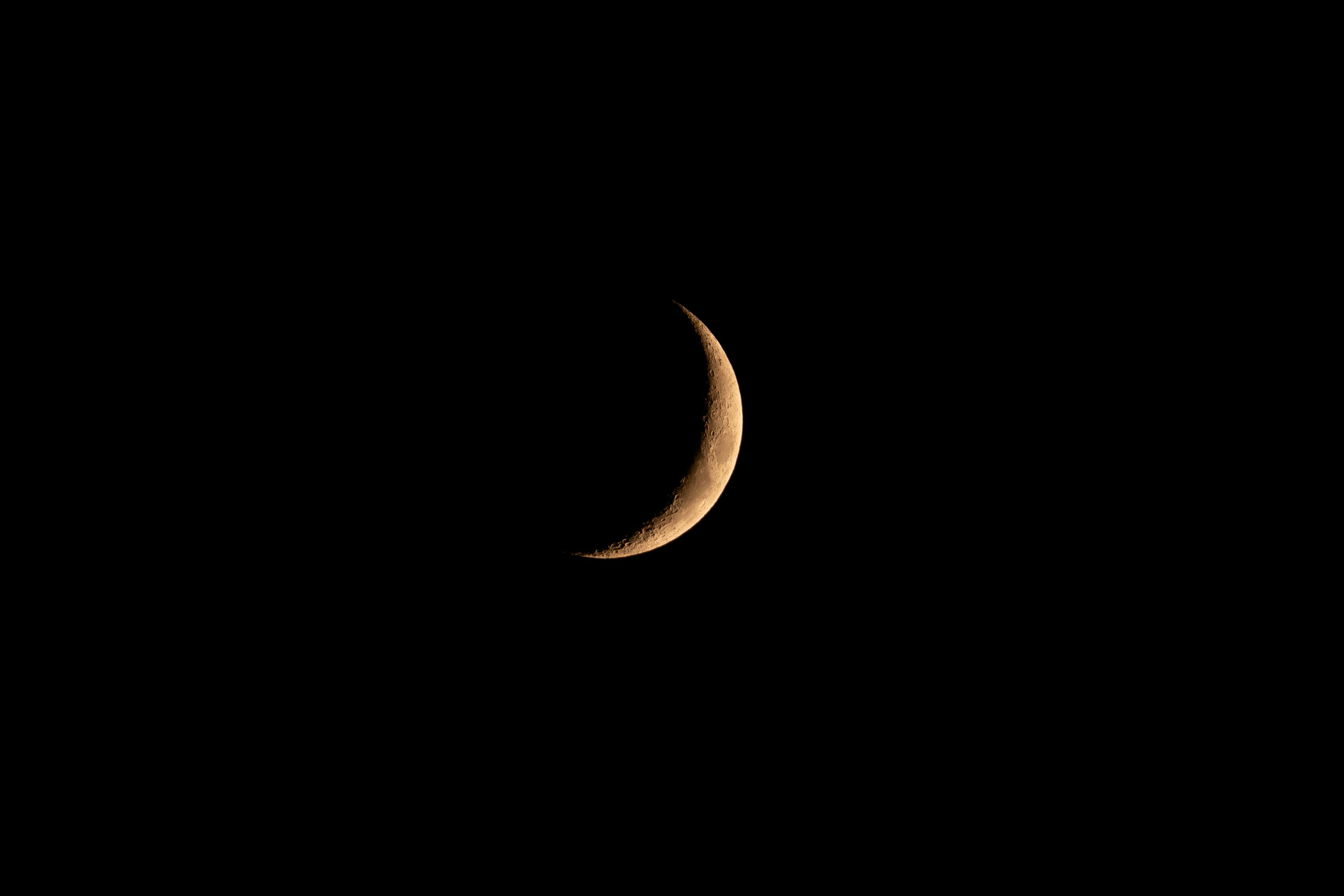 A striking crescent moon glows brightly against a deep black night sky.