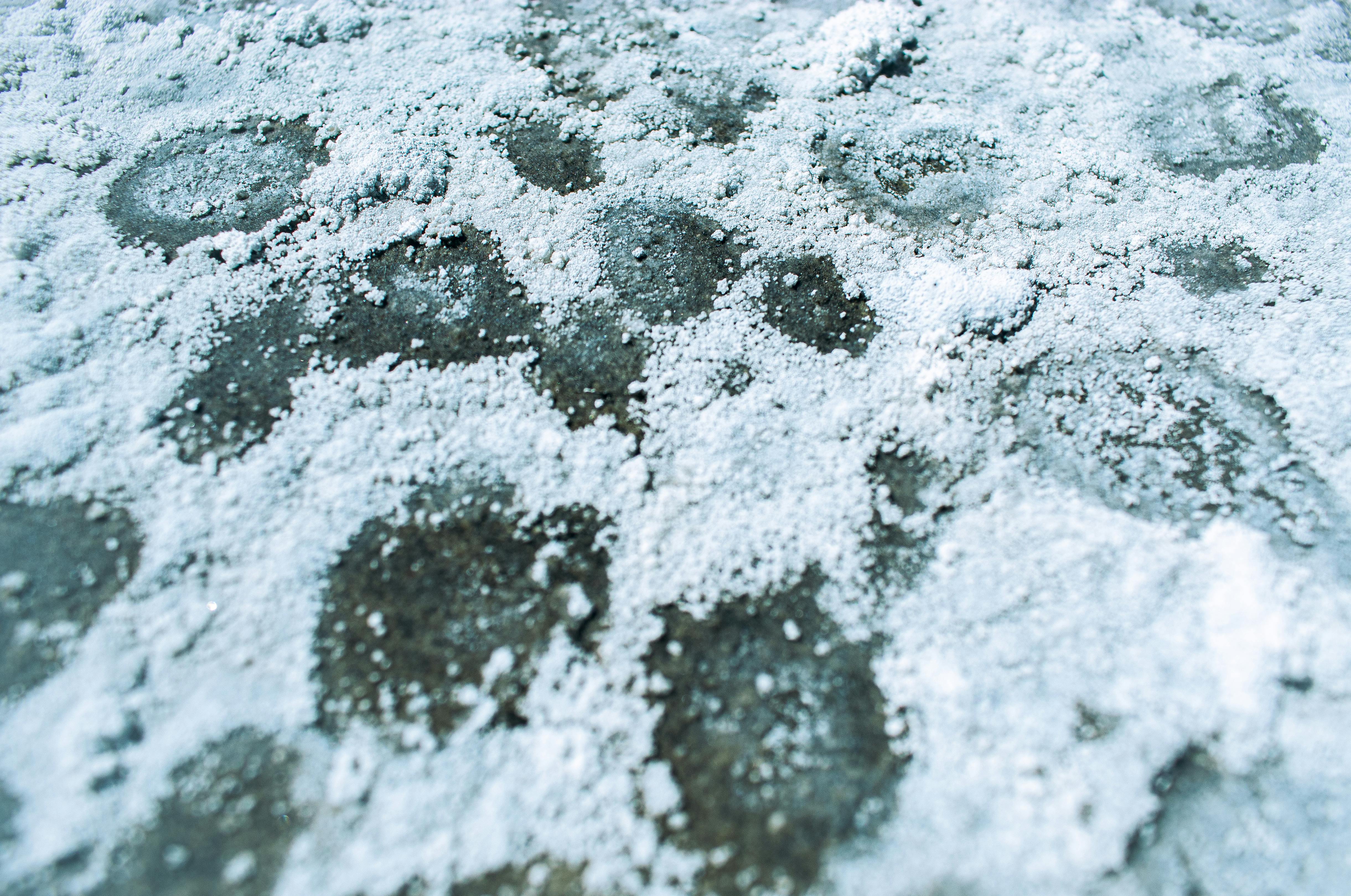 Close-up view of white salt deposits creating texture and pattern on a flat surface.