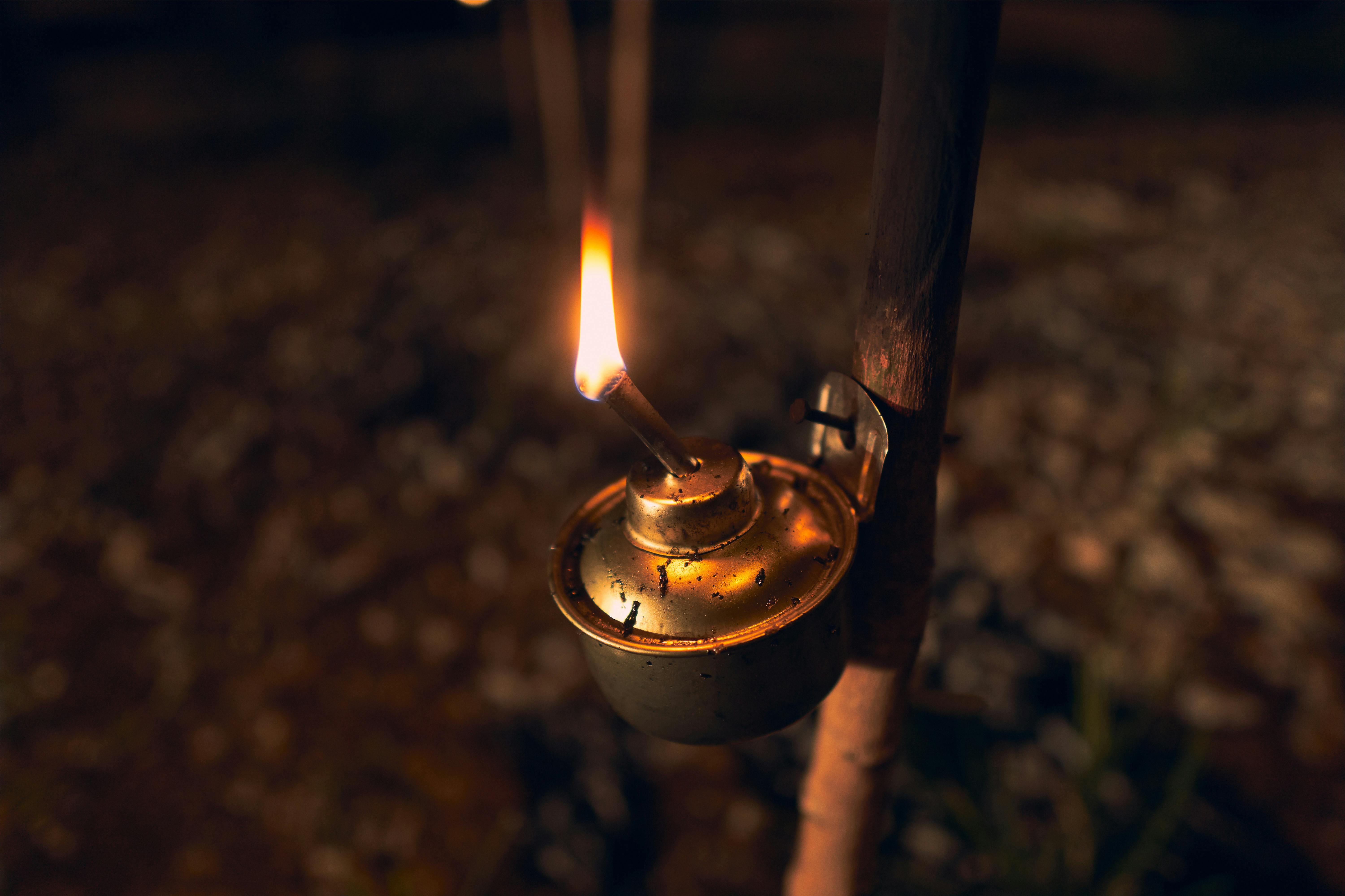 Close-up of a vintage kerosene lamp burning at twilight outdoors. Warm, nostalgic lighting.