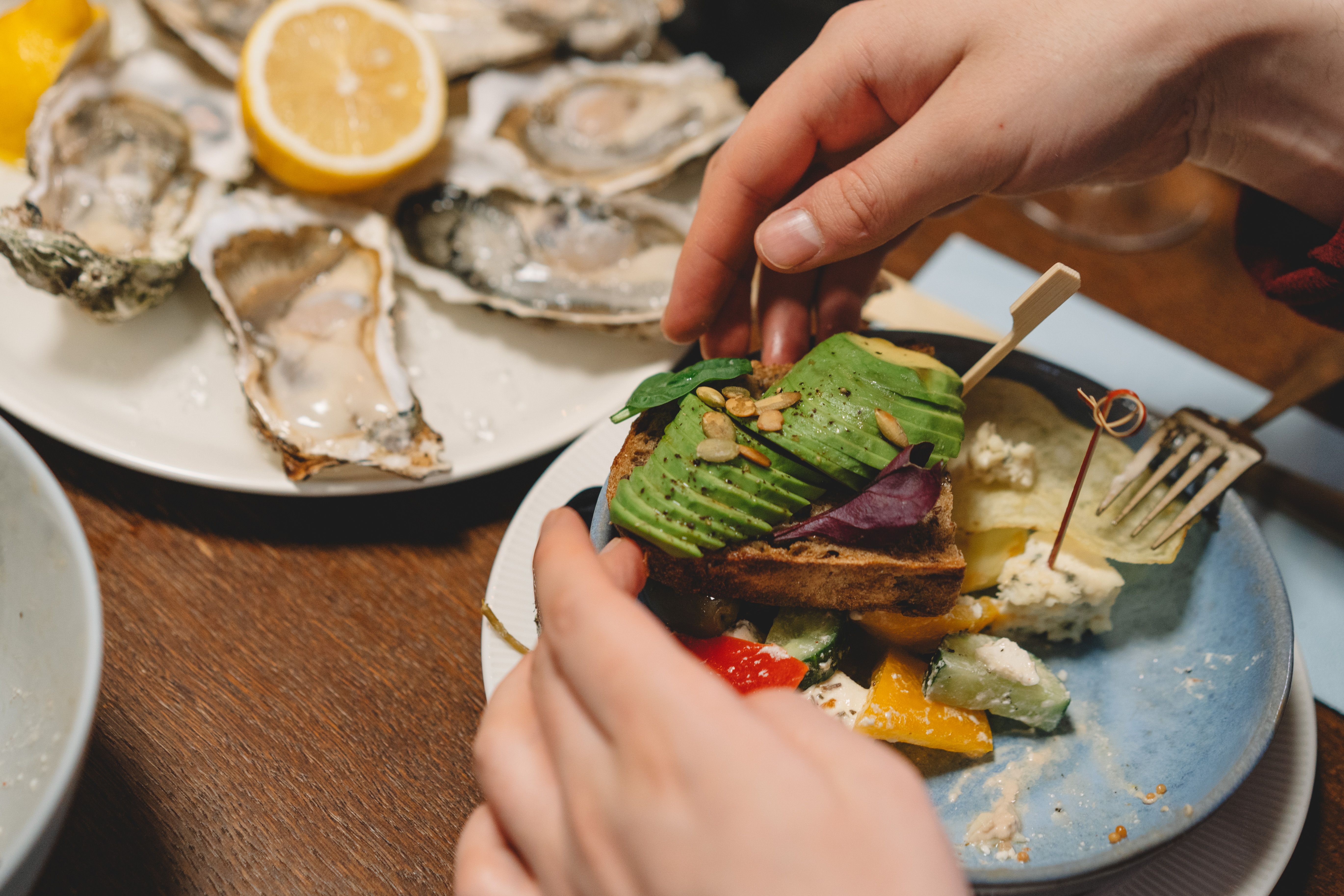 Delightful dinner scene featuring avocado toast and oysters with a lemon garnish.